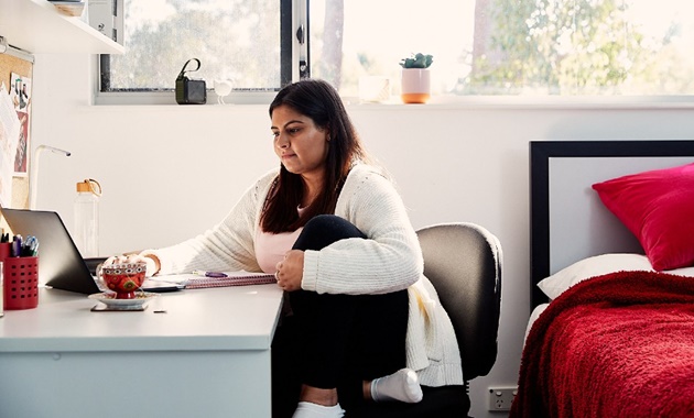 Student studying at a desk in her bedroom.