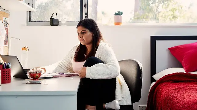 Student studying at a desk in her bedroom.