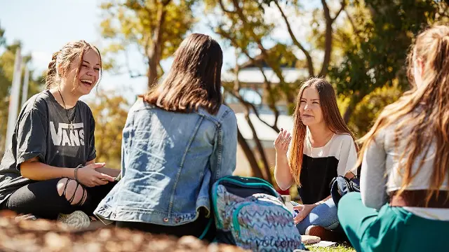 A group of students sitting and laughing together on Bush Court.