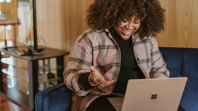 Woman sitting on sofa talking to someone through a laptop