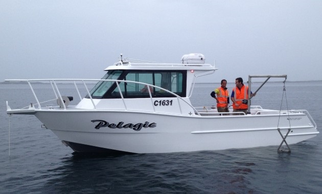 An MAFRL research vessel on the water with two researchers wearing life vests.