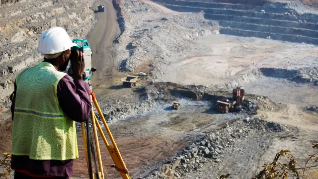 A locally employed surveyor surveying an open-pit copper mine in Zambia.