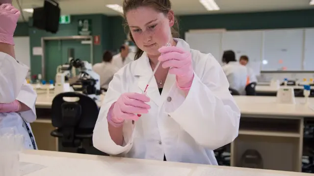 High school student working with a pipette in a science lab.