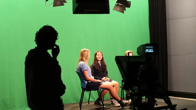 High school students against a green screen in a filming studio.