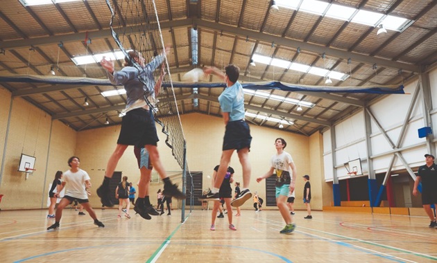 People playing volleyball on an indoor court.