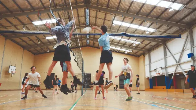 People playing volleyball on an indoor court.