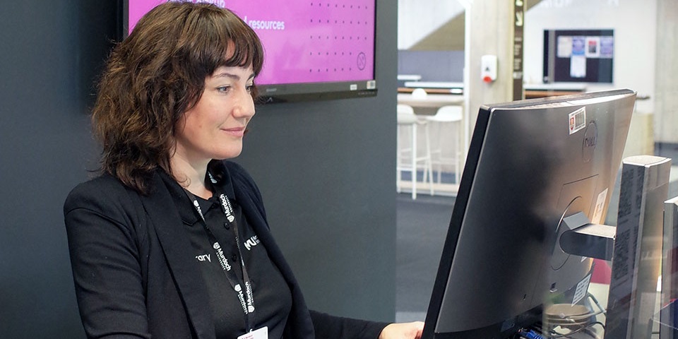 Librarian at help desk using computer