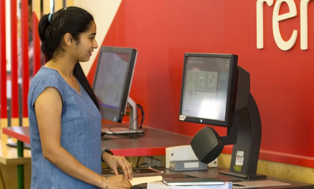 Student using a self check out machine at the Library