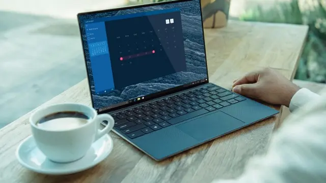 Dell laptop, open next to a cup of coffee.