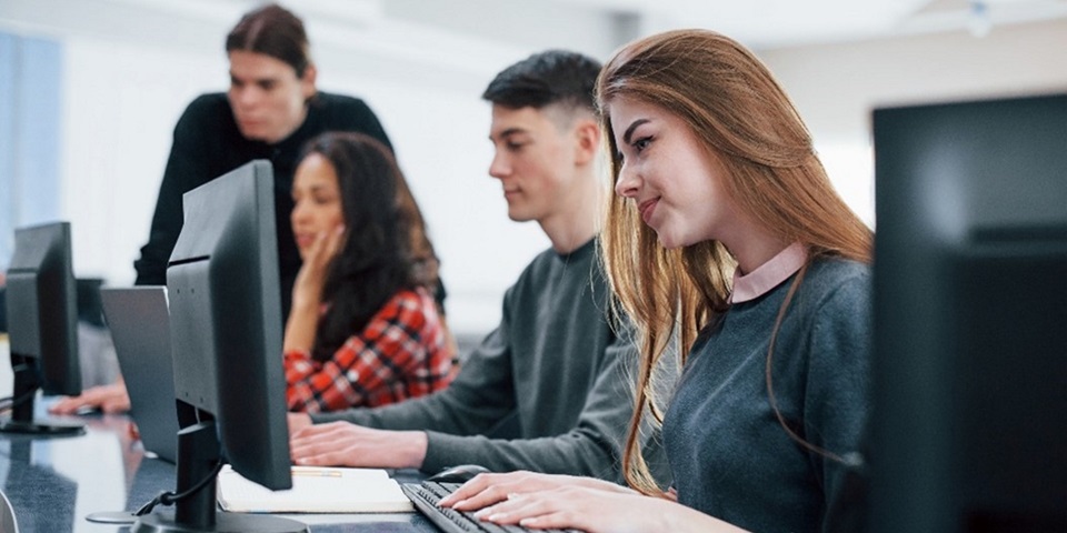 People typing at desktop computers with an instructor