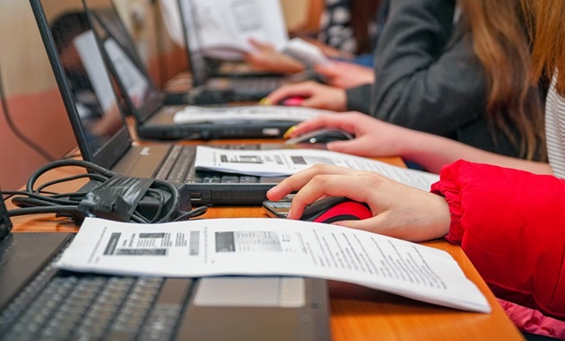 Row of people with laptops and instructional booklet