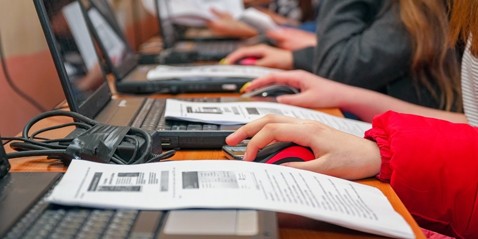 Row of people with laptops and instructional booklet