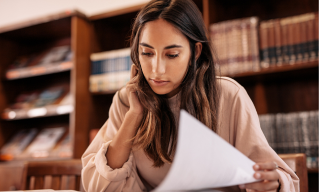 Person sitting in a library turning a page of a book