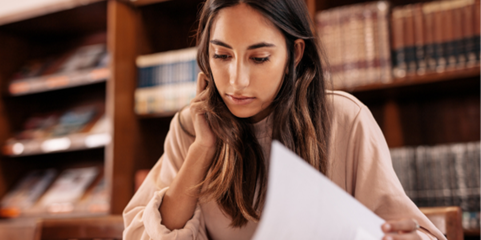 Person sitting in a library turning a page of a book
