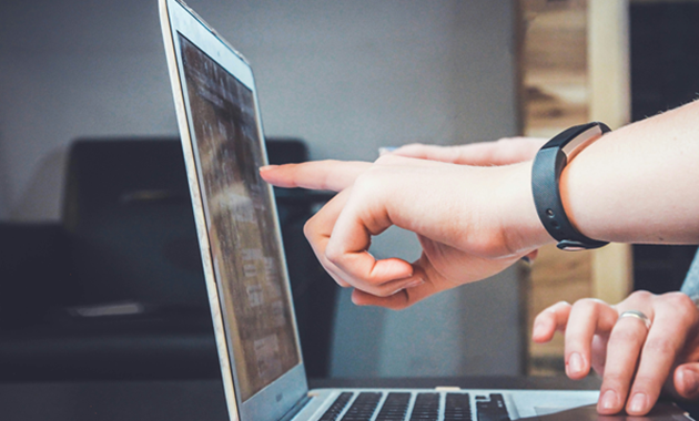 A person pointing at a laptop screen