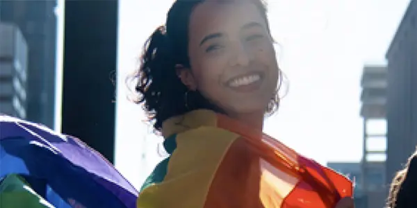 Woman with rainbow flag draped across shoulders
