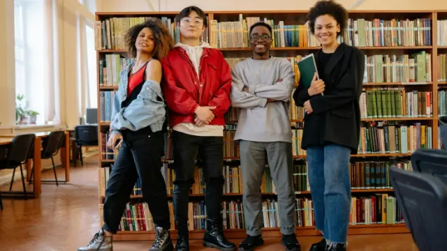 Four library staff posing in front of library shelves.