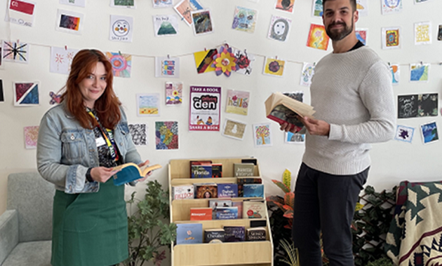 Man and woman standing on either side of the Little Free Libraries display