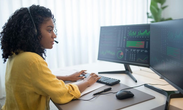 woman working at a desk top computer with two monitors