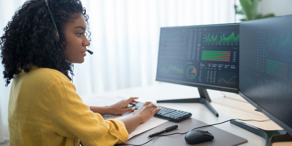 woman working at a desk top computer with two monitors