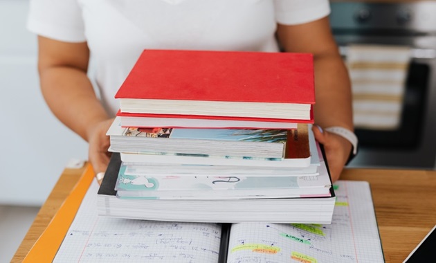 A person sets a pile of books on top of an open notebook.