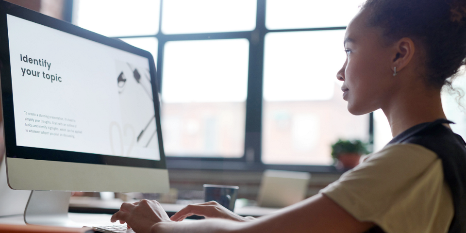 A woman at computer with "Identify your topic" written on the screen
