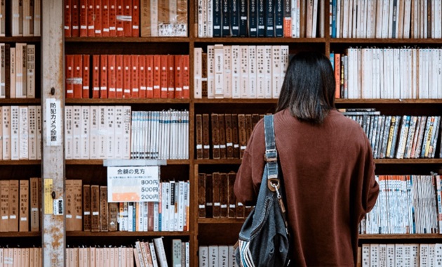 Person with back to camera browsing library shelves