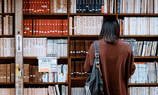 Person with back to camera browsing library shelves