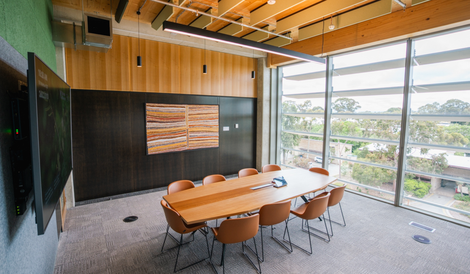 Room with tv and board room table and chairs in front of large window