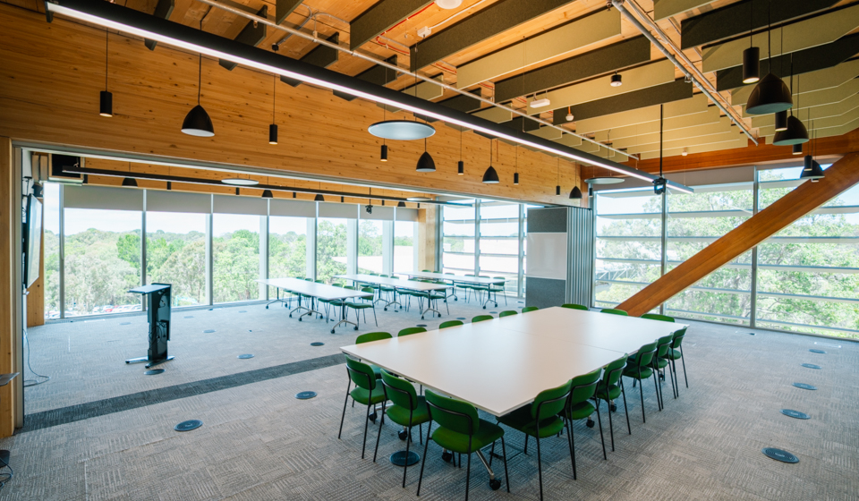 Large conference room with tables, chairs, and podium in front of large windows