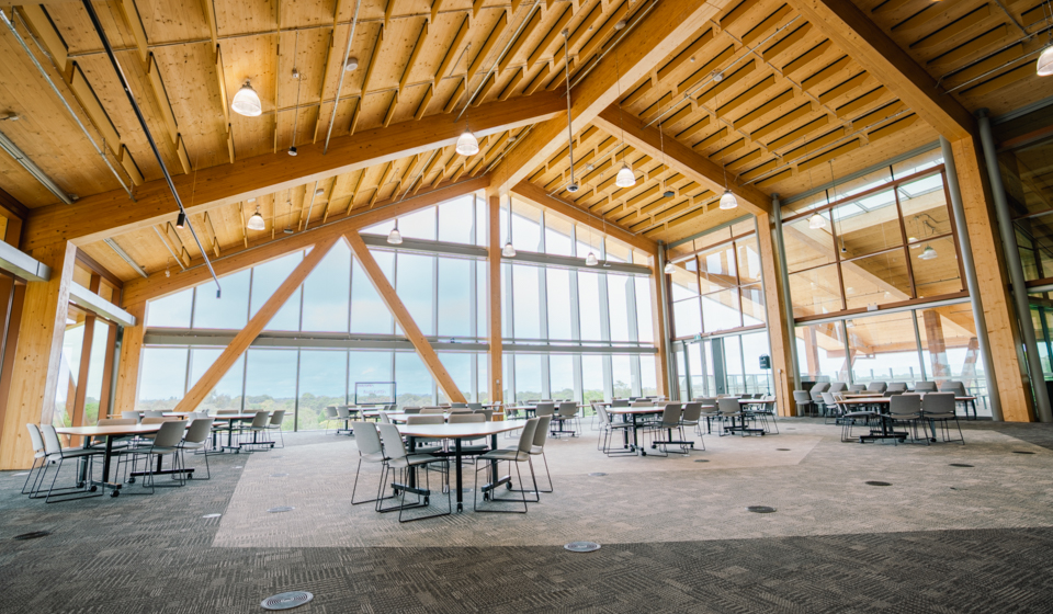 Large room with tables and chairs, featuring a timber roof and large windows