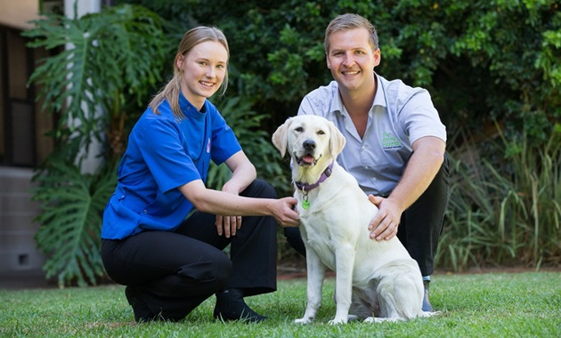 Two Animal Hospital staff members pose with a labrador