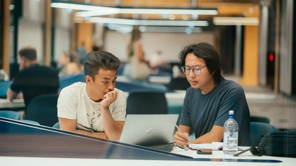 BK two students talking with laptop