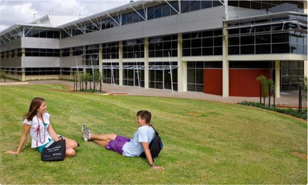 2 poeple sitting on grass outside research building