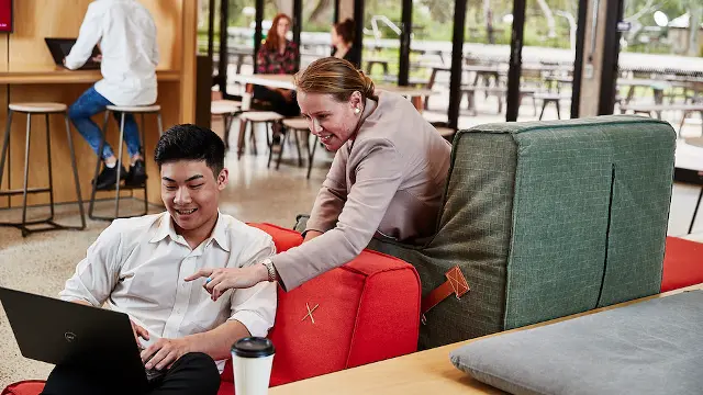 students helping over laptop