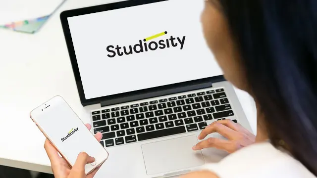 Student using computer and phone to access Studiosity services