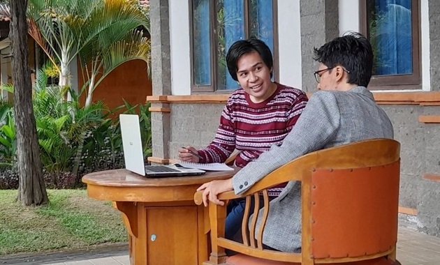 Student sits outside at a table with their laptop