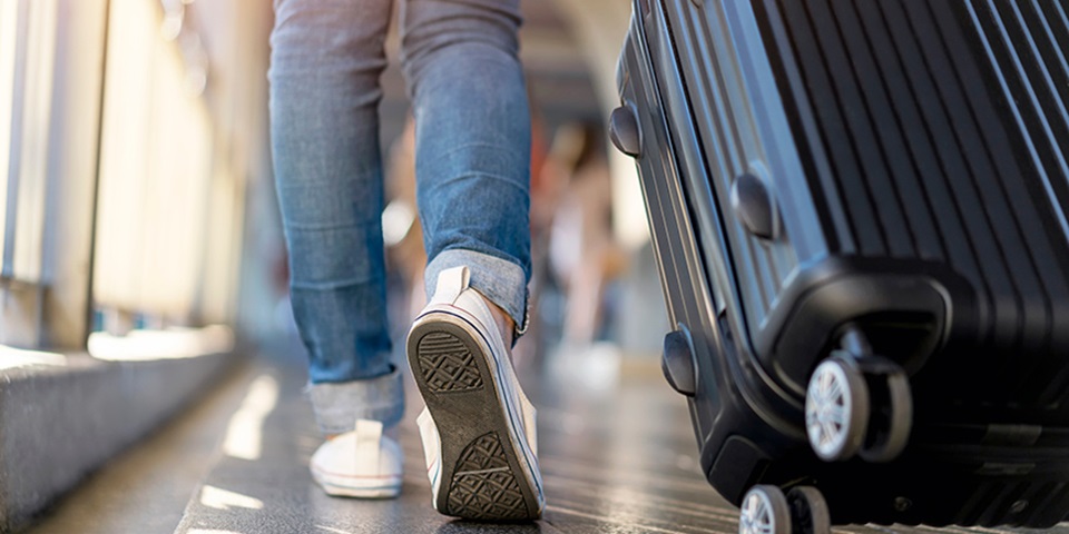 Arriving in Perth feature image Shot of legs in jeans and white converses walking in airport with a suitcase