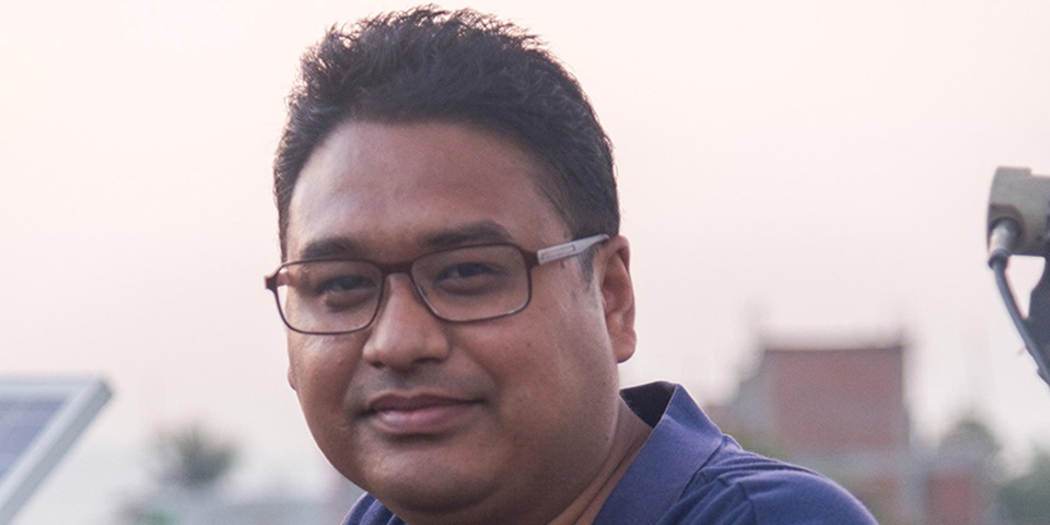 Avishek Malla feature image Murdoch alumnus Avishek Malla smiling at camera with solar panel in background