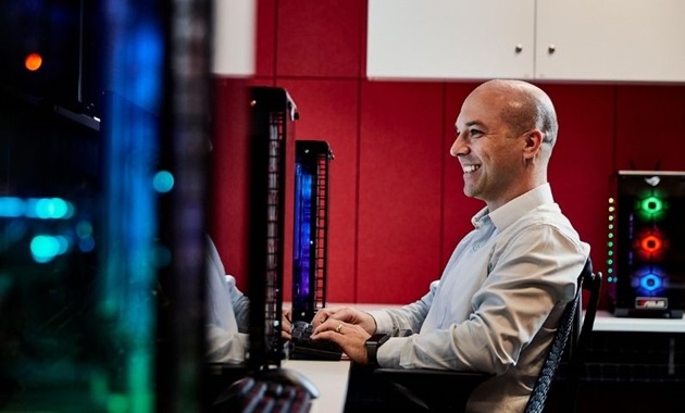 Student sits at computer desk smiling