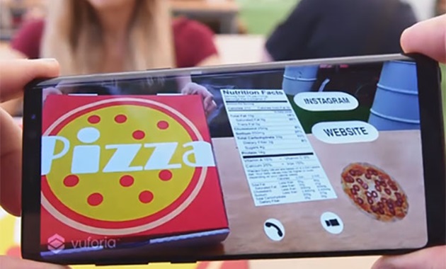 Fingers holding a smartphone which shows augmented reality information about a pizza