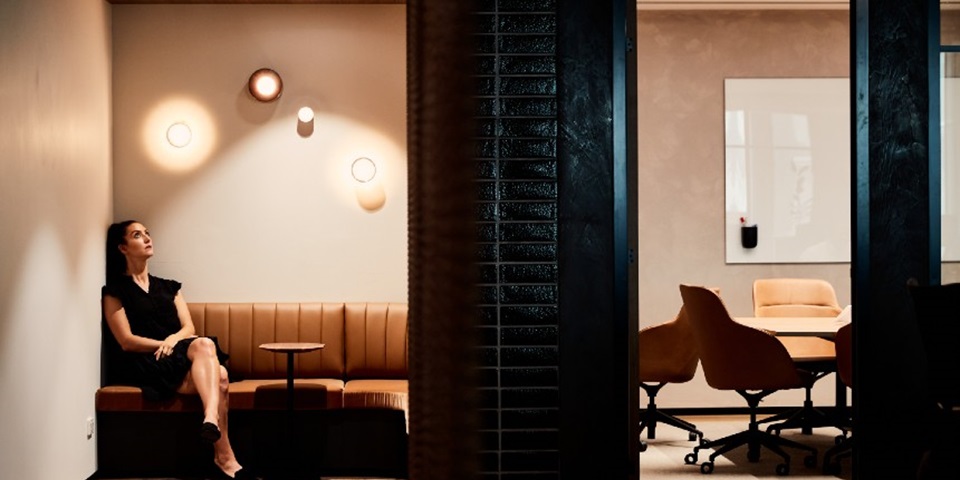 Girl sitting in office building looking up at light wondering