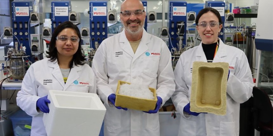 Three people posing in the lab holding biofoam boxes.