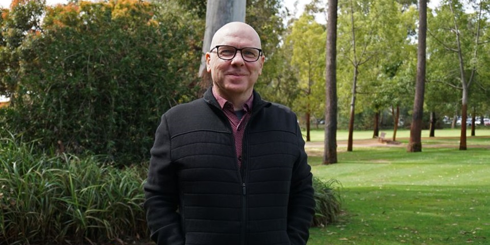 Dr Simon Adams standing amongst greenery on the Murdoch University campus.