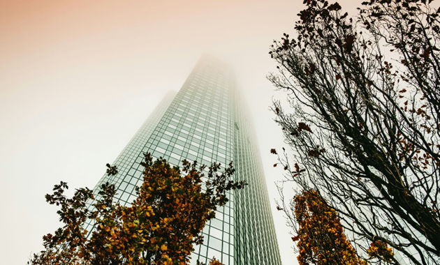 A tall skyscraper with trees growing outside