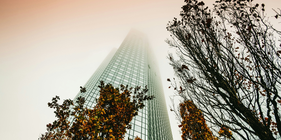 A tall skyscraper with trees growing outside