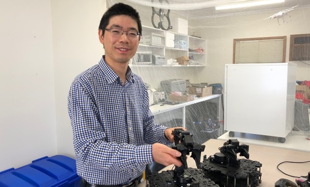 Dr Wai Hang in a lab with robots