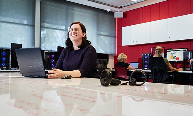 Female student sits in front of laptop in computer lab.