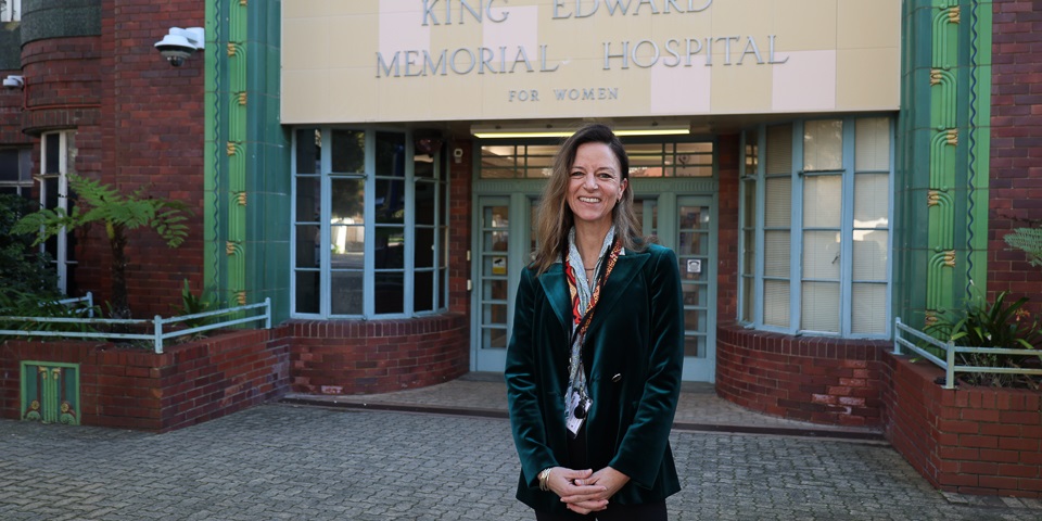 Kelli MacMillan standing in front of King Edward Memorial Hospital.