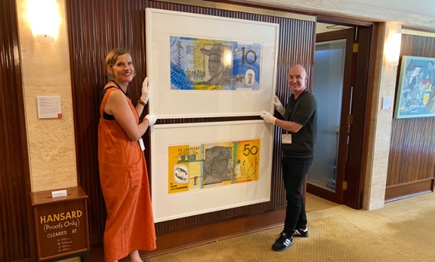 Murdoch curators Mark Stewart & Jane Chambers installing artworks resembling money by Ryan Presley